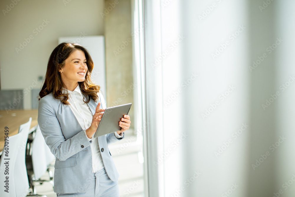 Young woman working on digital tablet by the office window Young woman working on digital tablet by the office window