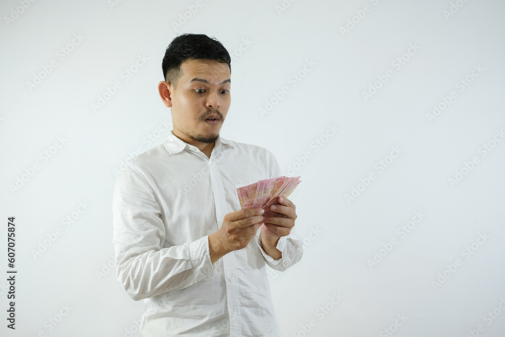 Adult Asian man holding paper money and showing shocked face expression