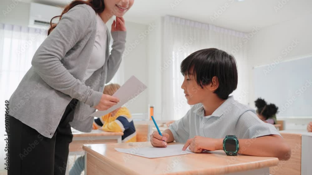 Group diverse students learning with woman teacher at elementary School.Young teacher woman handing out papers for exams to children sit on desk in classroom at school. Student Examination concept Group diverse students learning with woman teacher at elementary School.Young teacher woman handing out papers for exams to children sit on desk in classroom at school. Student Examination concept
