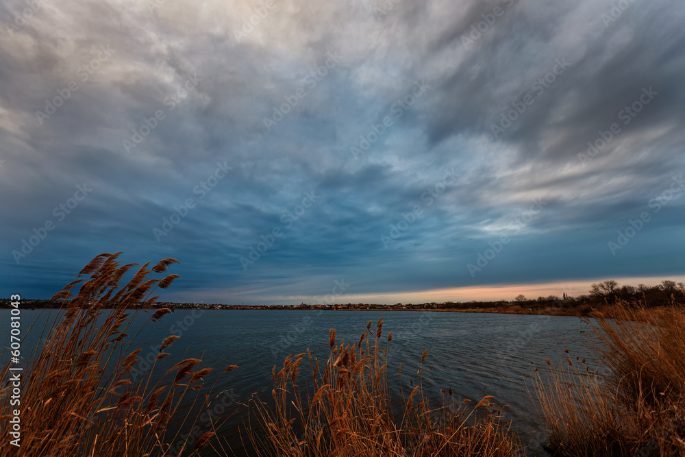 Late evening at the lake. Overcast and cloudy with reeds in the foreground