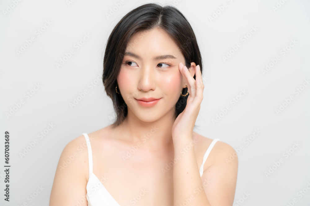 Asian woman touching her face and smiling happily. Close-up shot of an Asian woman's face with fair skin and healthy looking skin. Asian woman touching her face and smiling happily. Close-up shot of an Asian woman's face with fair skin and healthy looking skin.