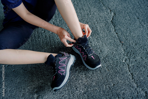 Photo of a woman tying her shoes, at that time she was running in the morning wearing sports shoes or sneakers
