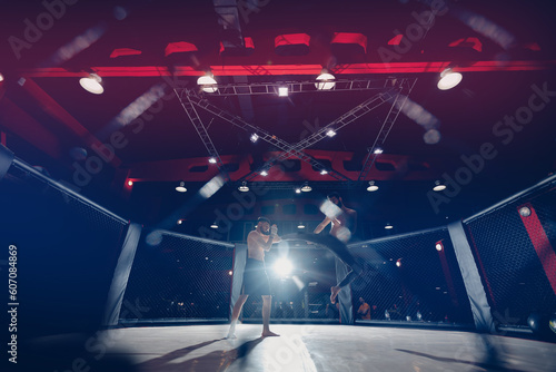 Boxers fighter finishes off enemy in MMA ring octagon, dark background spot light