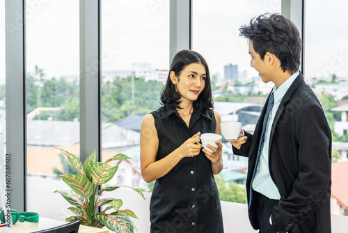 Nice coffee break, business woman drinking an espresso during a small talk with a young colleague while standing in office.