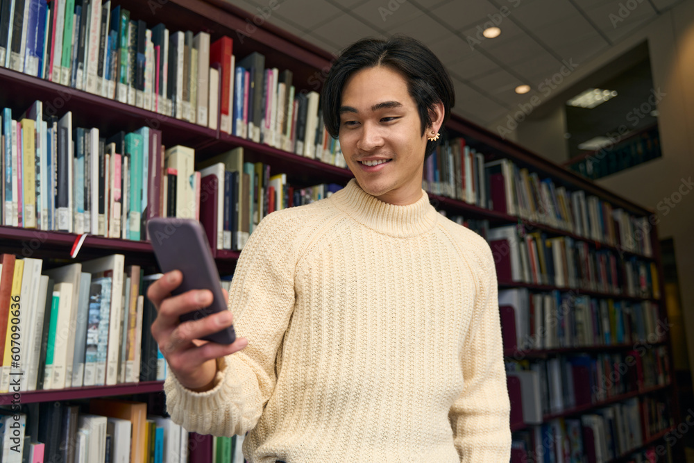 Happy asian university student checking social media in modern library Happy asian university student checking social media in modern library