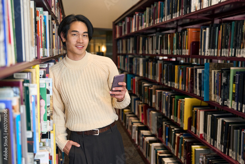 Stylish Japanese university student holding mobile phone and looking camera