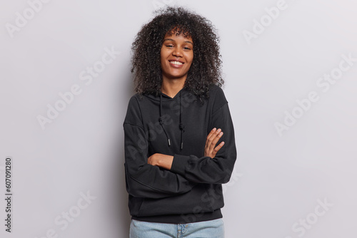 Canvas-taulu Indoor shot of cheerful self confident Afro woman keeps arms folded stands in as
