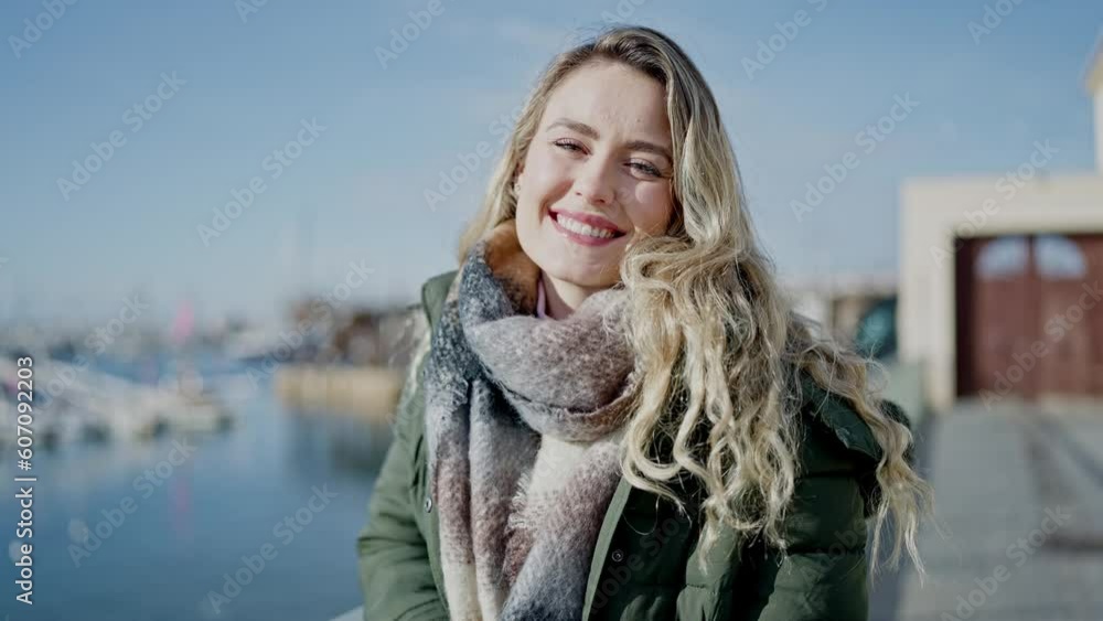 Young blonde woman smiling confident standing at seaside Young blonde woman smiling confident standing at seaside