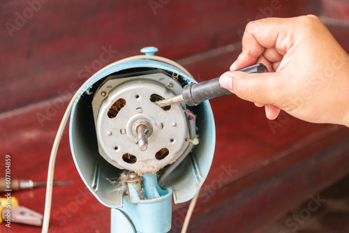 A mechanic hand is using a screwdriver to repair a broken fan.