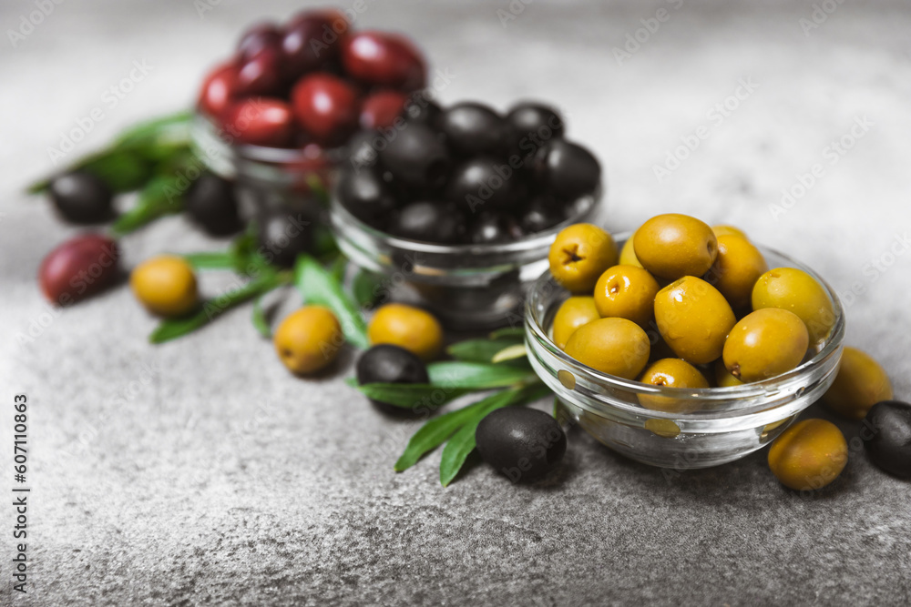 A set of green, red and black olives on a black marble background. Different types of olives in bowls and olive oil with fresh olive leaves. Delicacy.Mediterranean Kitchen. Copy space. A set of green, red and black olives on a black marble background. Different types of olives in bowls and olive oil with fresh olive leaves. Delicacy.Mediterranean Kitchen. Copy space.