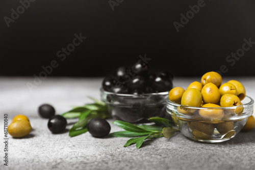 Fototapeta Naklejka Na Ścianę i Meble -  Green and black olives on a textured background. Different types of olives in bowls and olive oil with fresh olive leaves. Delicacy.Mediterranean Kitchen. Copy space.