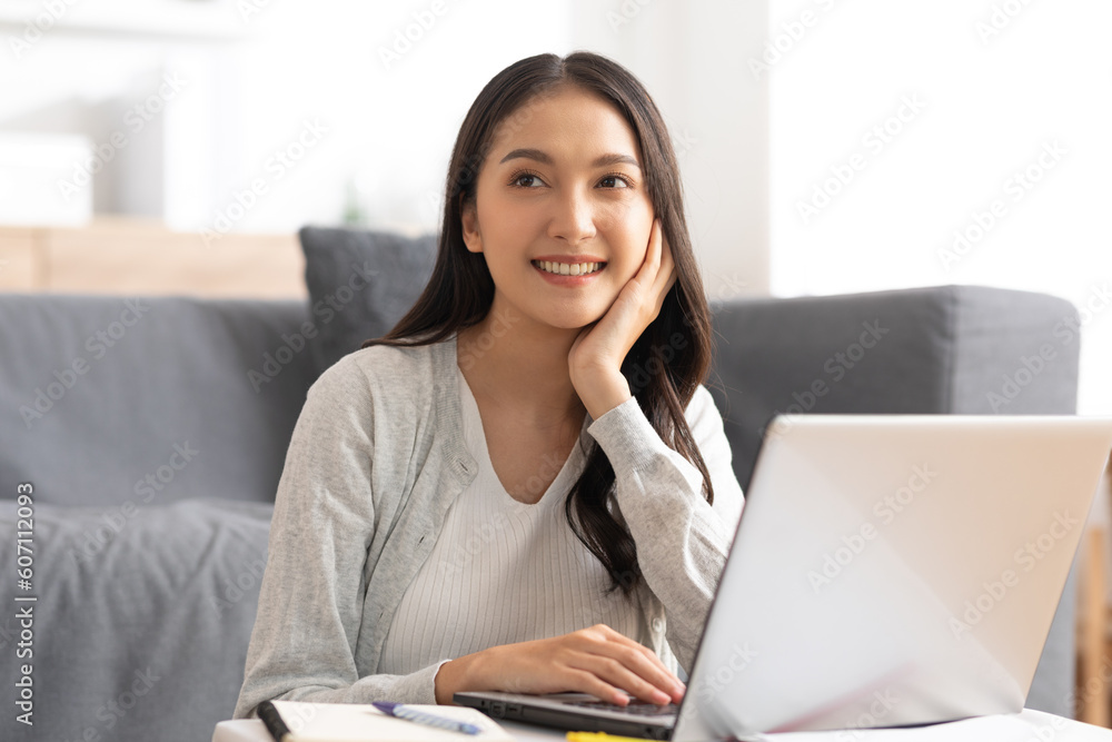 beautiful asian young woman wear casual sit on couch using computer laptop entertain with social media relax smile and laughing.Freelance woman working online sale marketing. Shopping online at home beautiful asian young woman wear casual sit on couch using computer laptop entertain with social media relax smile and laughing.Freelance woman working online sale marketing. Shopping online at home