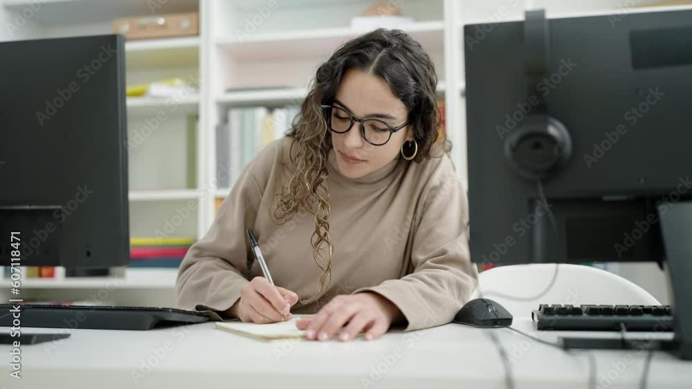 Young beautiful hispanic woman student using computer taking notes at library university