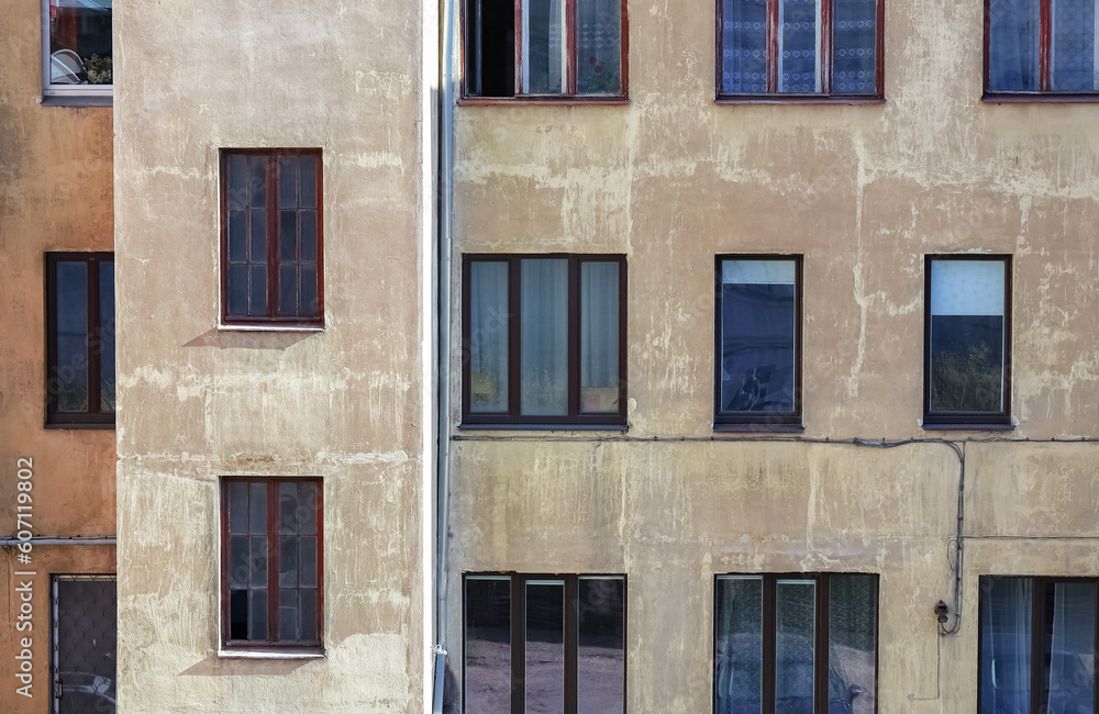 Obraz premium Wall of brown building with stailess steel water pipe and many different windows with various objects and people inside