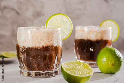 Fotografi Homemade dirty soda with cola and lime in glasses on the table