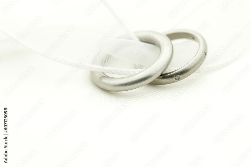 Naklejka premium Close up of wedding rings on white band with copy space on white fabric Focus on rings