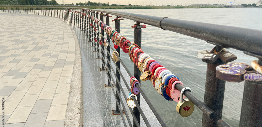 Many colorful locks on the metal railings near the river. Banner