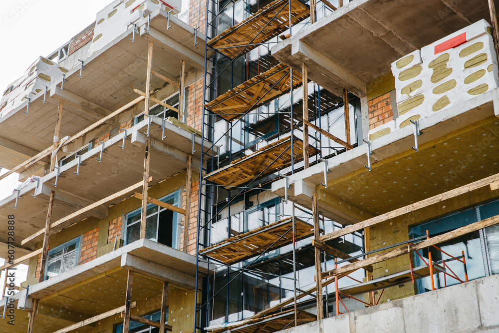 scaffolding on the facade of a house under construction with building materials scaffolding on the facade of a house under construction with building materials