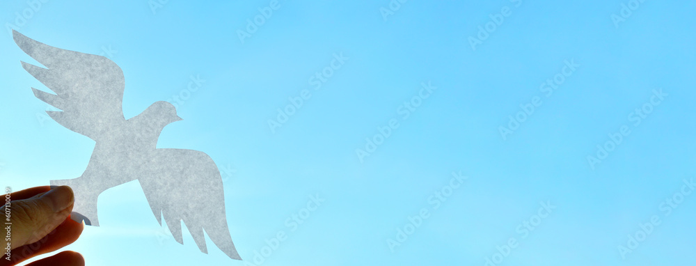 Obraz premium White paper origami bird on blue sky background. World Day of Peace. Day Against Humiliation. International Day Of Human Fraternity. International Day of Living Together in Peace. Banner