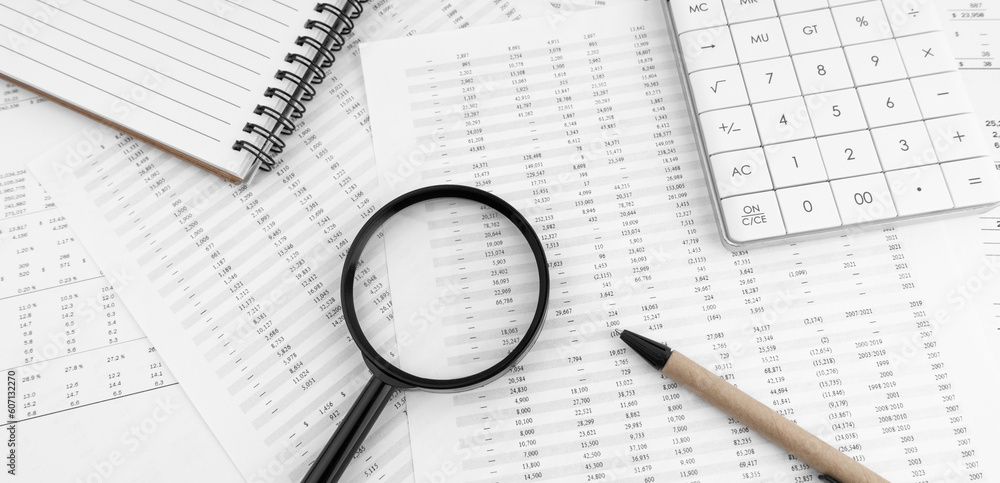 Calculator, magnifying glass and notebook lying on financial statement. Calculator, magnifying glass and notebook lying on financial statement.