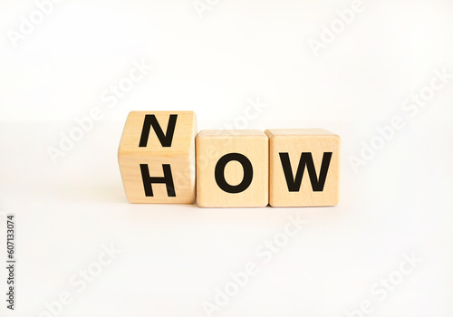Now how symbol. Businessman turns wooden cubes and changes the word How to Now. Beautiful white table white background. Copy space. Business and now how concept.