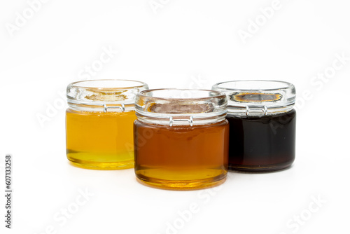 Jars with three different types of honey isolated on a white background