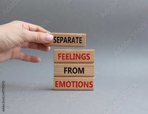 Feelings and Emotions symbol. Concept word Separate Feelings from Emotions on wooden blocks. Beautiful grey background. Doctor hand. Psychology and Feelings and Emotions concept. Copy space