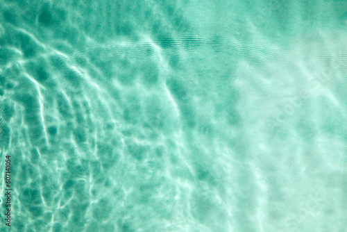 Abstract textured background, water waves in the pool with sun reflection, clear blue water