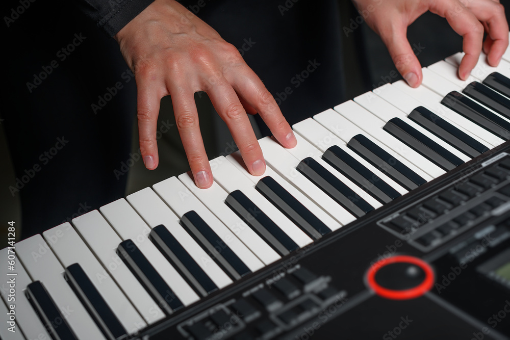Obraz premium Playing a synthesizer on a dark background. The musician plays the synthesizer.