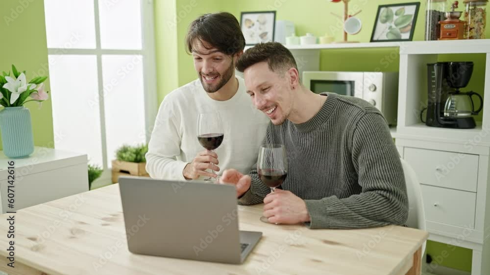 Two men couple having video call drinking glass of wine at dinning room Two men couple having video call drinking glass of wine at dinning room