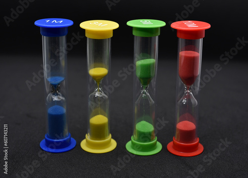 Multicolored glass hourglass on a black background. Vintage hourglass.