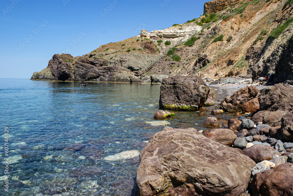 Black Sea coast, Cape Fiolent, Crimea, Ukraine. Royal beach. The sea has transparent turquoise water. There are large smooth stones on the shore.