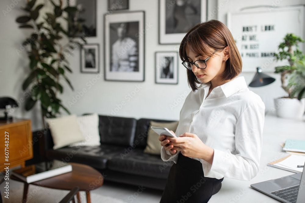 Attractive woman freelancer using modern cellphone, standing near table working at coffee shop, copy space Attractive woman freelancer using modern cellphone, standing near table working at coffee shop, copy space
