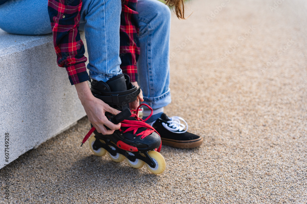 Young woman putting on roller skates in park closeup