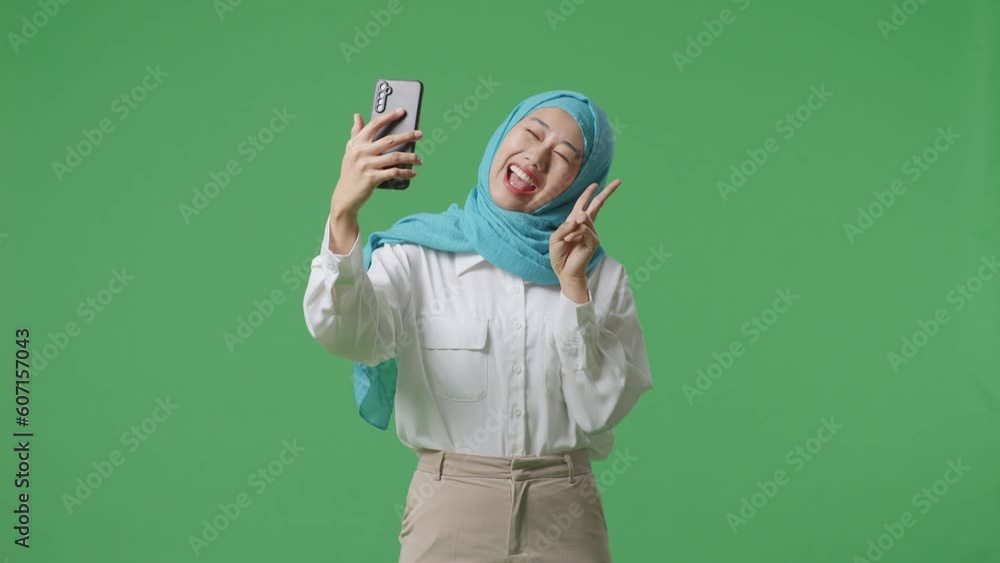 Asian Muslim Woman Smiling And Using Smartphone Taking Picture While Standing In The Green Screen Background Studio
Asian Muslim Woman Smiling And Using Smartphone Taking Picture While Standing In The Green Screen Background Studio