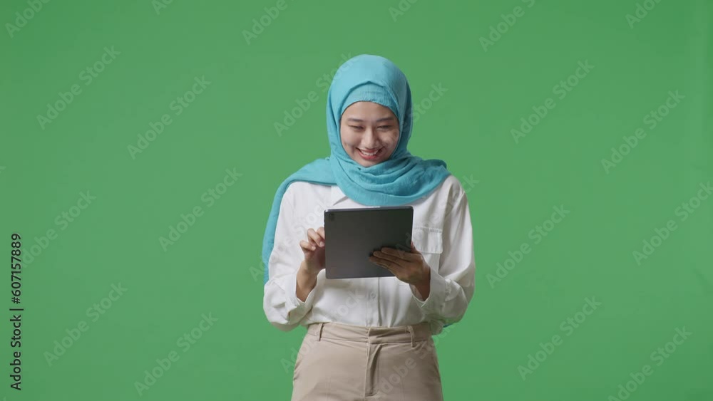 Asian Muslim Woman Smiling And Using Tablet Then Pointing To It While Standing In The Green Screen Background Studio
Asian Muslim Woman Smiling And Using Tablet Then Pointing To It While Standing In The Green Screen Background Studio