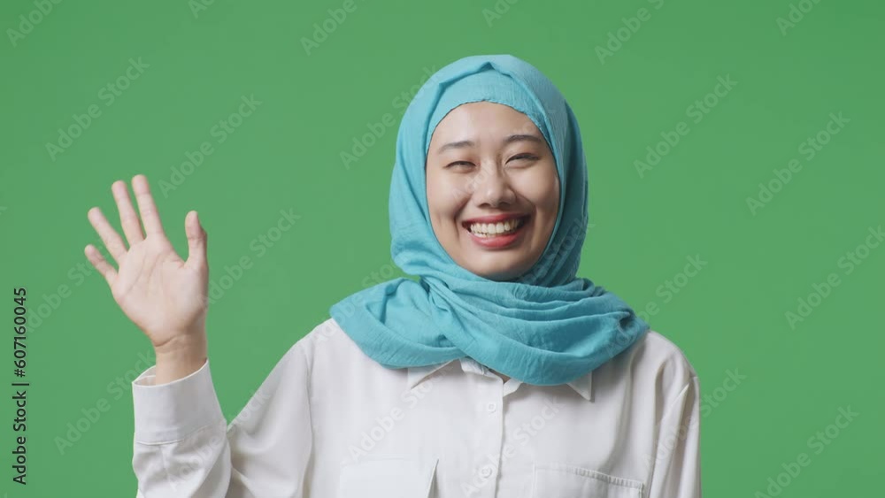 Close Up Of Asian Muslim Woman Smiling And Waving Hand Greeting The Camera While Standing In The Green Screen Background Studio
Close Up Of Asian Muslim Woman Smiling And Waving Hand Greeting The Camera While Standing In The Green Screen Background Studio