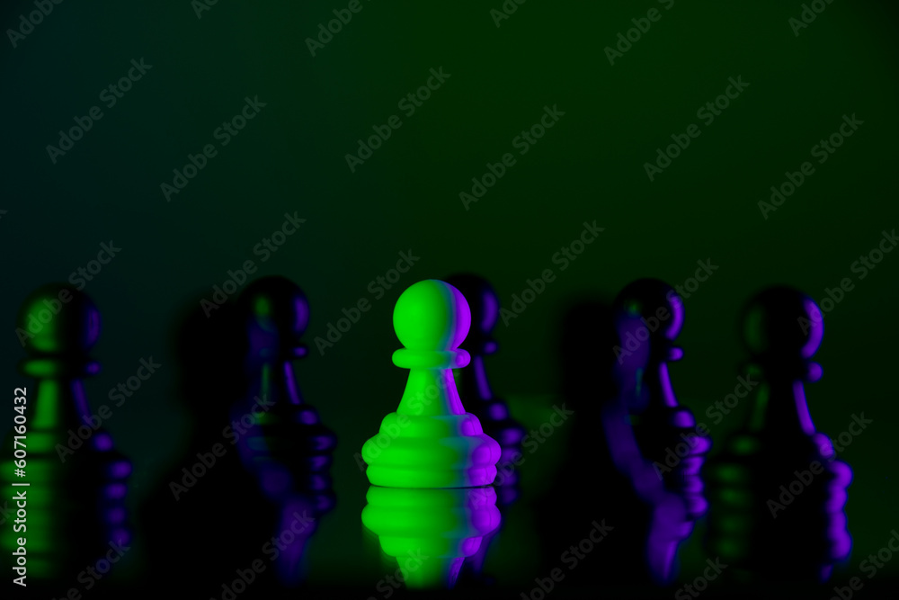 The white pawn is surrounded by black pawns. The concept of bullying. Neon lights in the dark
