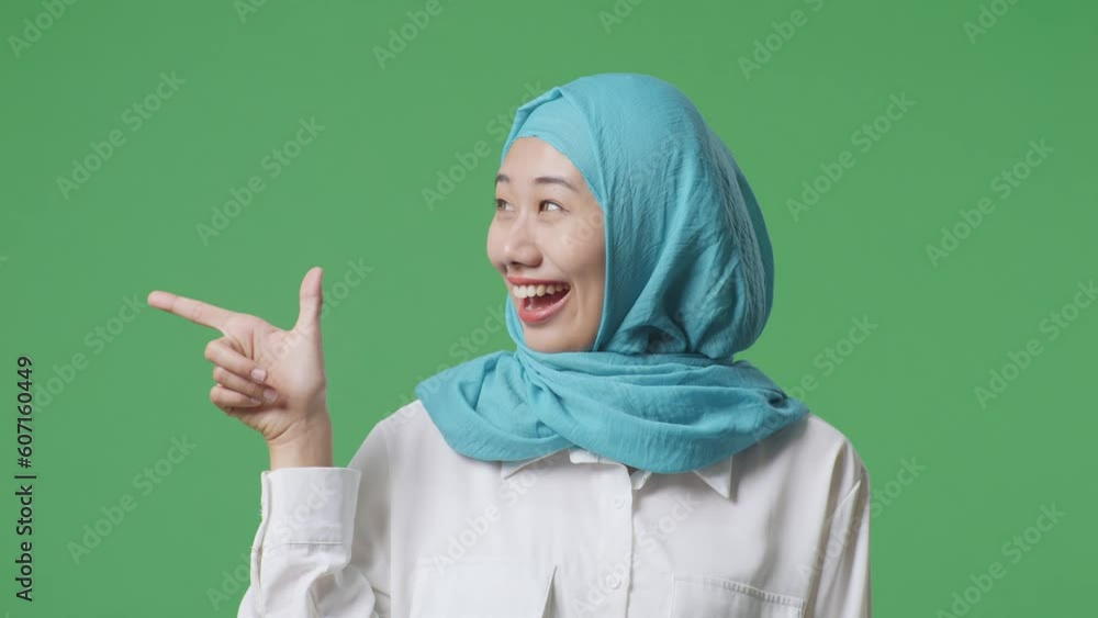 Close Up Of Asian Muslim Woman Smiling And Pointing To Side While Standing In The Green Screen Background Studio
Close Up Of Asian Muslim Woman Smiling And Pointing To Side While Standing In The Green Screen Background Studio