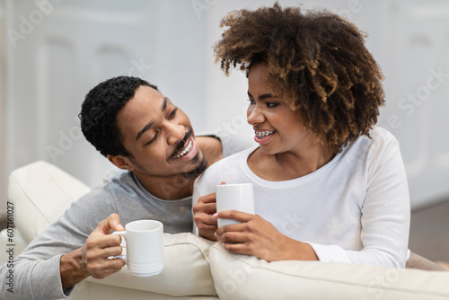 Closeup of cheerful black couple drinking coffee at home