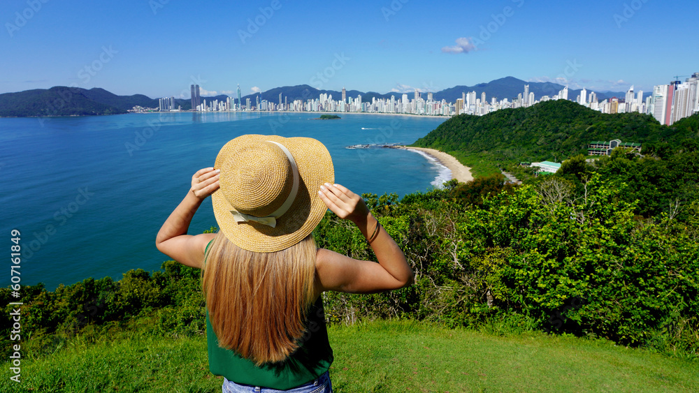Vacation in Brazil. Panoramic view of traveler girl on viewpoint enjoying Balneario Camboriu skyline, Brazil.