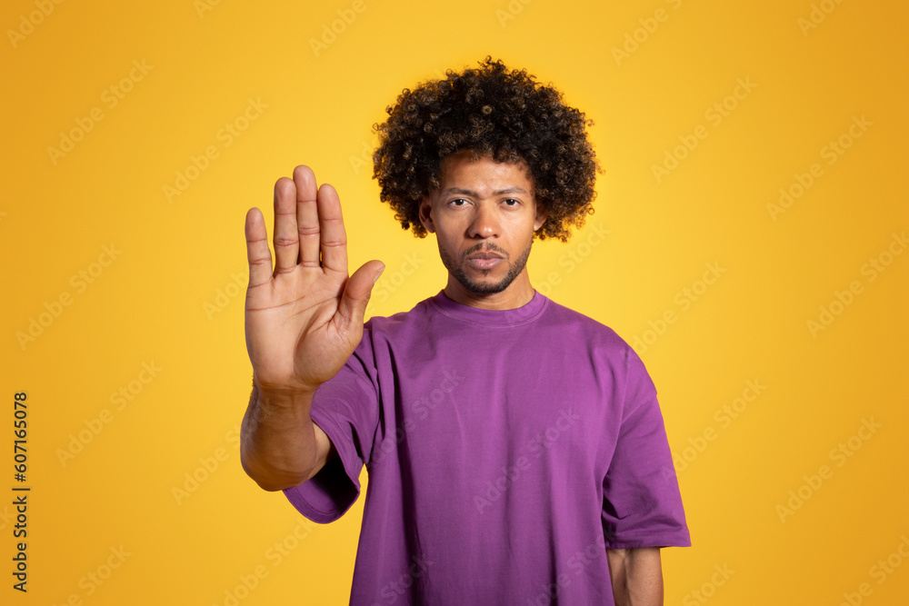 Serious confident mature black curly man in purple t-shirt making stop gesture with hand Serious confident mature black curly man in purple t-shirt making stop gesture with hand