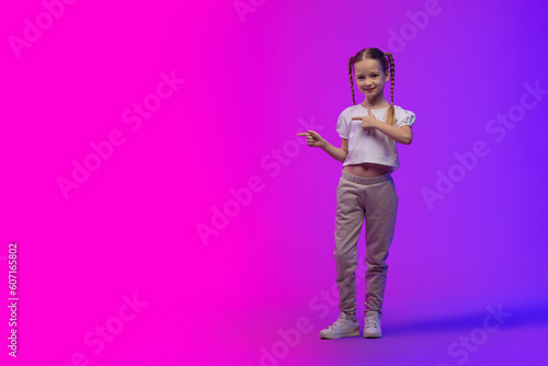 Pretty little girl pointing at copy space, futuristic background