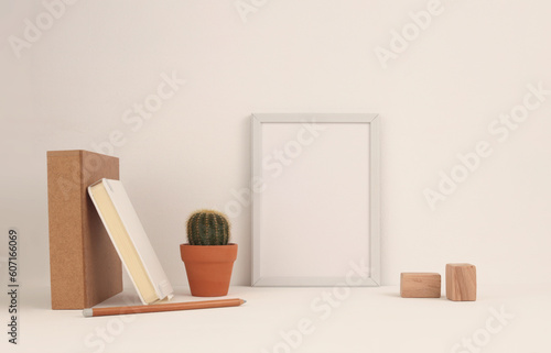 Office table (shelf) with empty frame and decorative objects. Copy space creative ligt beige workspace. © Liliia