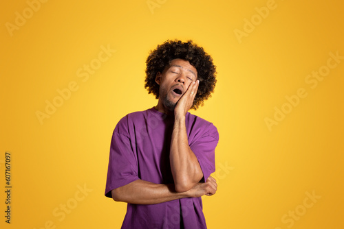 Tired exhausted funny bored mature black curly man in purple t-shirt sleeping with open mouth © Prostock-studio