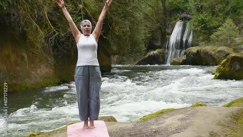 Active Woman Practicing Yoga on a rocky beach by the river photo