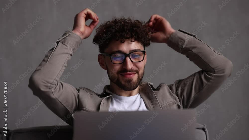 Young man with laptop on couch relaxing hands over head at home Young man with laptop on couch relaxing hands over head at home