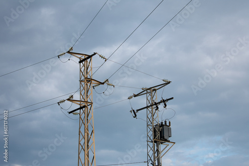 High-power electricity poles in the urban area connected to the smart grid. Power supply, power distribution, power transmission, high voltage concept photo. Cloudy sky. Malaga, Spain.