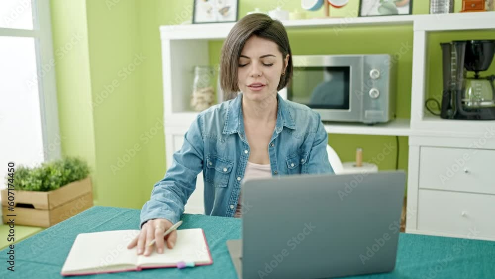 Young caucasian woman having video call writing on notebook at home Young caucasian woman having video call writing on notebook at home