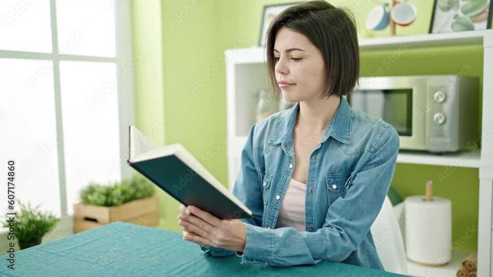 Young caucasian woman reading book sitting on table at home Young caucasian woman reading book sitting on table at home